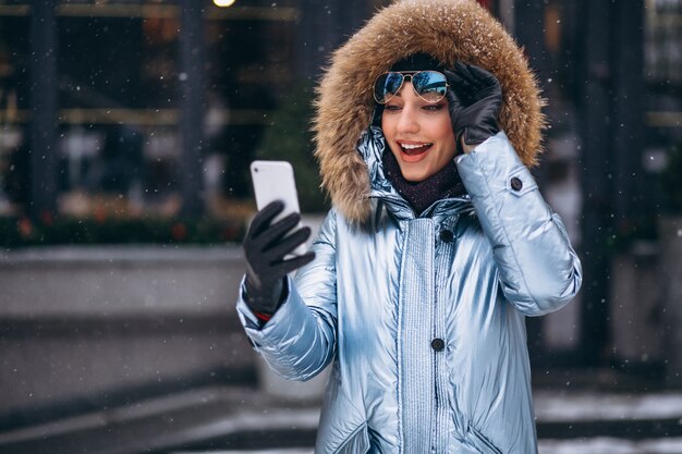 Femme heureuse en veste bleue parlant au téléphone