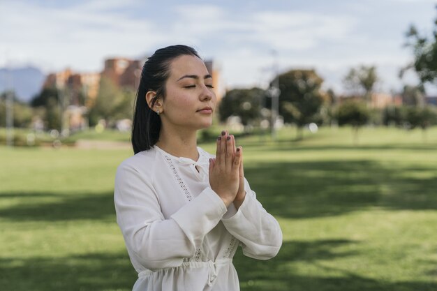 Femme hispanique faisant du yoga dans un parc