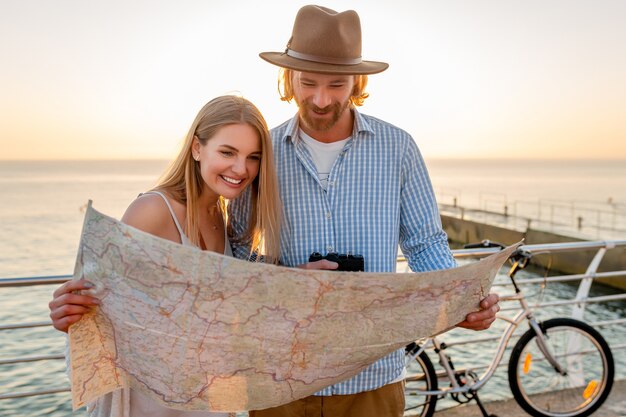 Femme et homme amoureux voyageant à vélo au coucher du soleil sur la mer