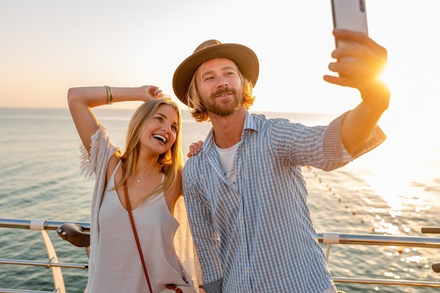 Femme et homme amoureux voyageant à vélo au coucher du soleil sur la mer