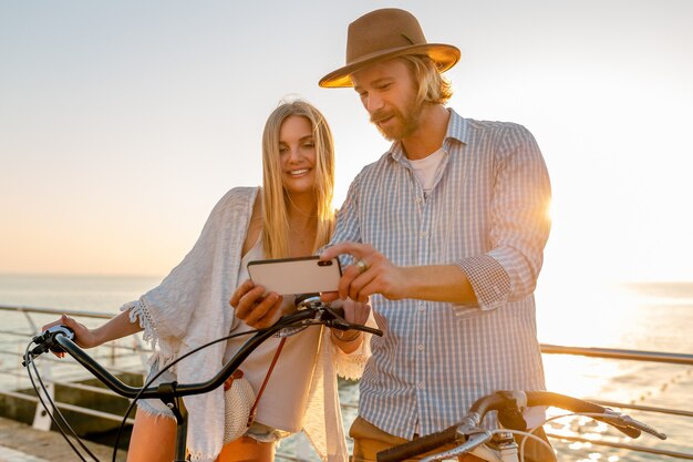 Femme et homme amoureux voyageant à vélo au coucher du soleil sur la mer