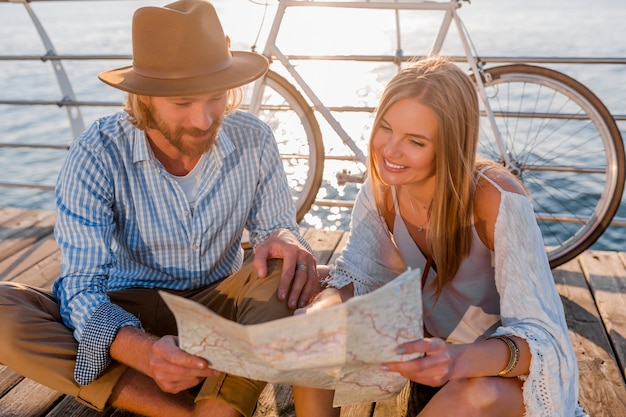 Photo gratuite femme et homme amoureux voyageant à vélo au coucher du soleil sur la mer