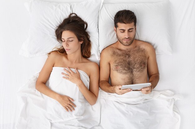 Femme et homme assis dans le lit vue de dessus