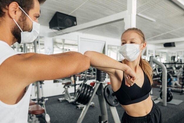 Femme et homme faisant le salut du coude à la salle de sport