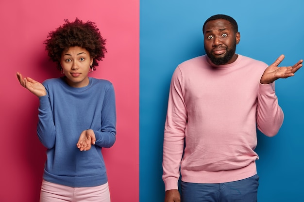 Photo gratuite une femme et un homme noirs interrogés hésitants haussent les épaules avec des expressions ignorantes, n'ont aucune suggestion, écarquillent les paumes du doute, prennent une décision