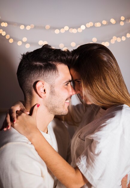 Femme et homme souriant embrassant dans une pièce sombre