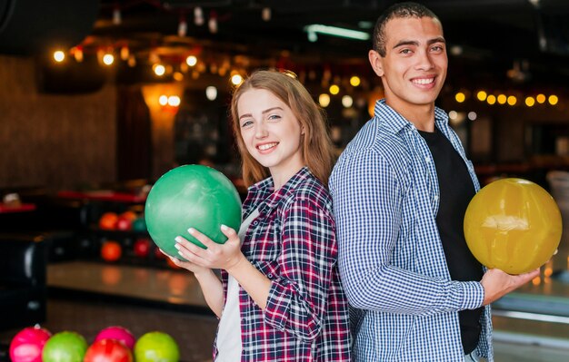 Femme et homme tenant les boules de bowling colorées