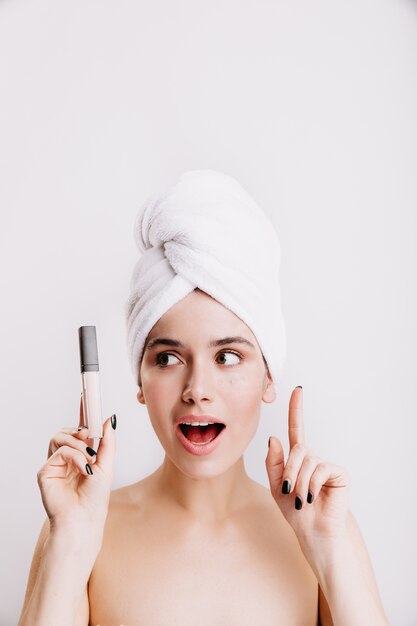 La femme a une idée de comment améliorer le teint de son visage. Portrait de femme au cours de la routine du matin avec correcteur à la main.