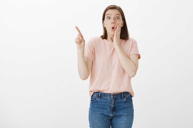 Femme impressionnée et surprise montrant la promo, pointant vers la gauche et l'air étonné