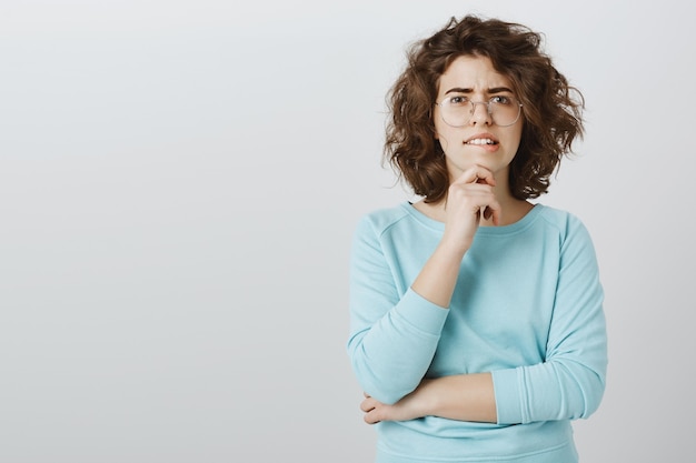 Femme incertaine et indécise faisant un choix, se mordant la lèvre en pensant