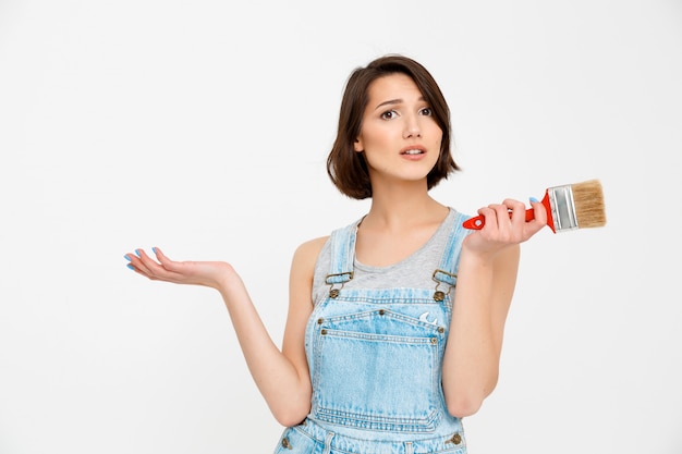 Une femme indépendante répare elle-même à la maison, tient un pinceau