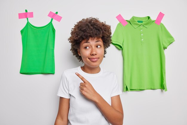 la femme indique loin montre des vêtements décontractés verts vêtus de poses de t-shirt blanc décontracté montre des vêtements à porter. Regarde ça