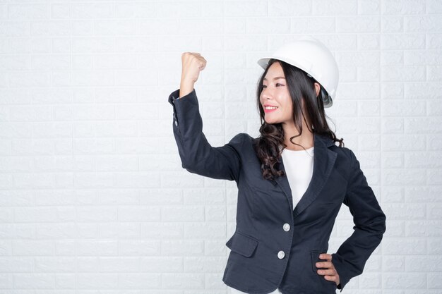 Femme d&#39;ingénierie tenant un chapeau, Séparer le mur de briques blanches fait des gestes avec la langue des signes.