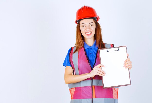 Femme ingénieur en uniforme tenant un fichier de rapport vierge.