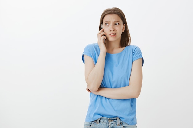 Femme inquiète parlant au téléphone avec le visage concerné, demandant de l'aide