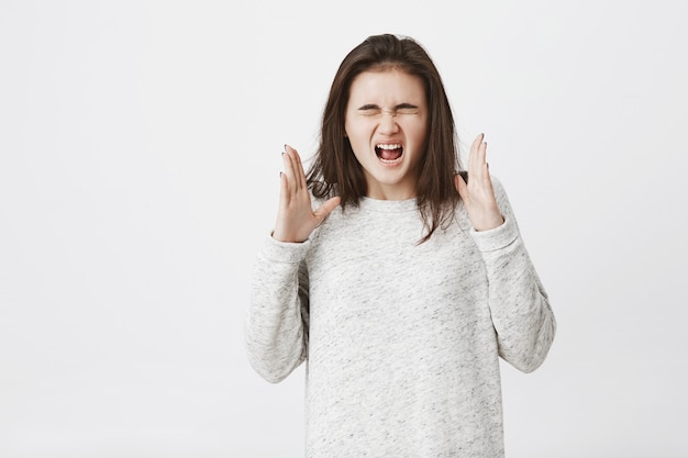 femme insatisfaite et folle, qui crie les yeux fermés et fait des gestes, exprimant sa colère.