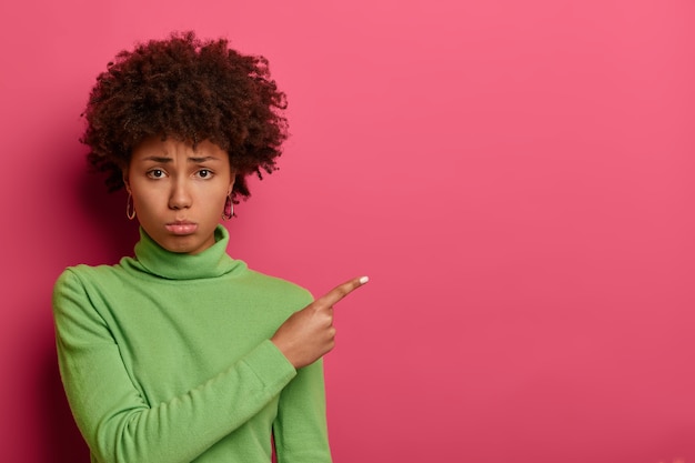 Une femme insatisfaite malheureuse montre un espace vide, serre les lèvres et demande conseil avec déception, étant très bouleversée, ne croit pas à la bonne chance