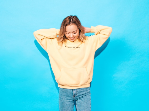 femme insouciante posant près du mur bleu en studio. Modèle positif s'amusant