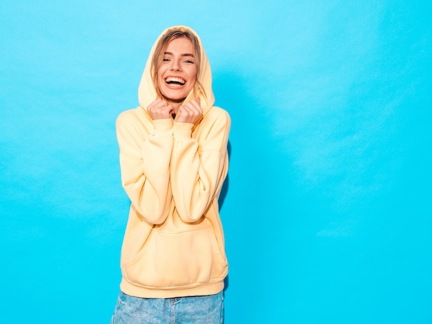 femme insouciante posant près du mur bleu en studio. Modèle positif s'amusant