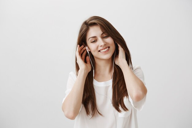 Femme insouciante souriante, écouter de la musique dans des écouteurs