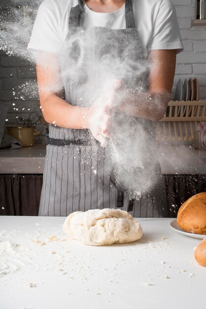 Femme jetant de la farine sur la pâte