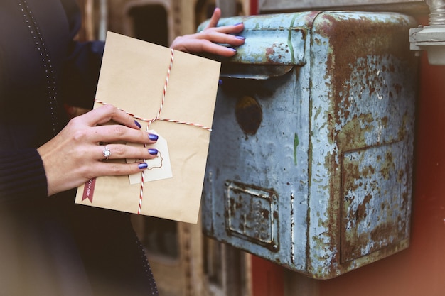 femme jette une enveloppe de père Noël dans une vieille boîte aux lettres vintage