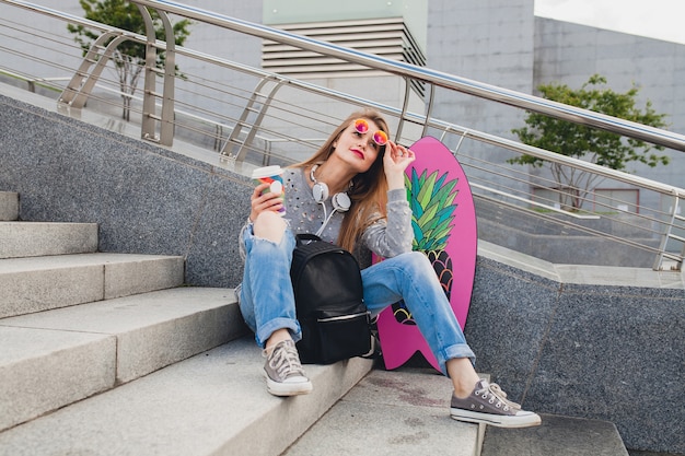 Femme jeune hipster dans la rue avec planche d'équilibre portant pull et jeans