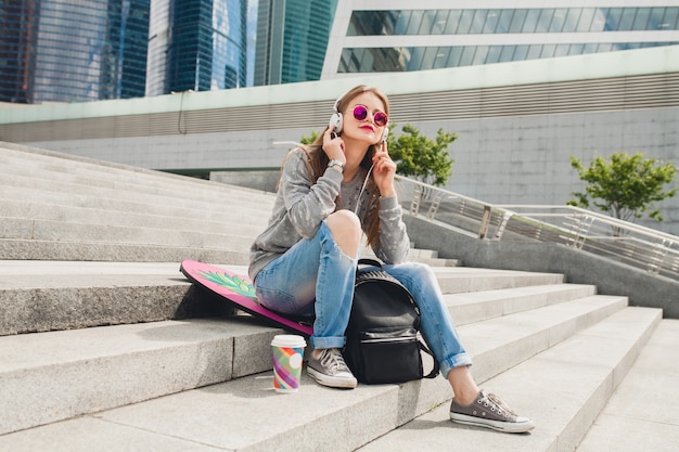 Femme jeune hipster dans la rue avec planche d'équilibre portant pull et jeans