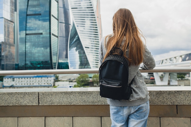 Femme jeune hipster s'amuser dans la rue, écouter de la musique sur des écouteurs, porter des lunettes de soleil roses et sac à dos, style urbain printemps été, à la recherche sur la ville