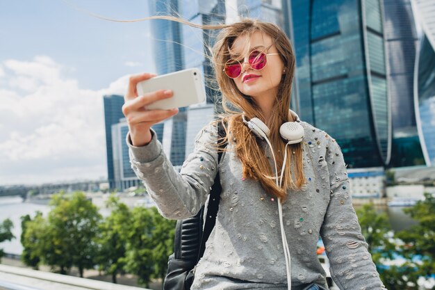 Femme jeune hipster s'amuser dans la rue, portant des lunettes de soleil roses