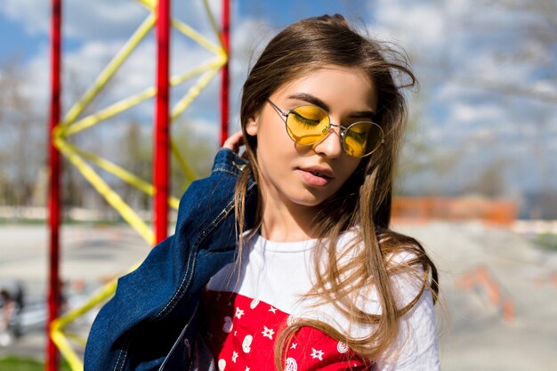 Femme jeune hipster sportive s'amuse et pose au soleil, portant des t-shirts spectaculaires et des bretelles lumineuses, ville urbaine, flash. Détendre les émotions, le calme