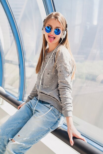 Femme jeune hipster en tenue décontractée s'amusant à écouter de la musique au casque