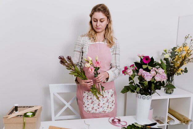 Photo gratuite femme jolie fleuriste prépare des fleurs dans la boutique