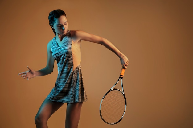 Photo gratuite femme jouant au tennis isolé sur mur marron