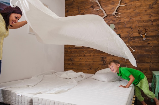 Photo gratuite femme jouant avec un enfant en train de faire du lit