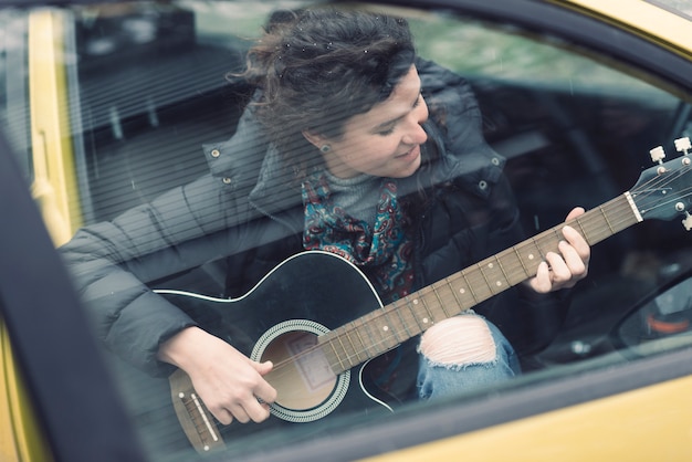 Femme jouant de la guitare dans la voiture