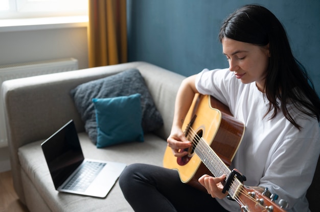 Femme jouant de la guitare à la maison pendant la quarantaine