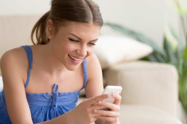 Femme jouant à des jeux mobiles sur téléphone portable à la maison