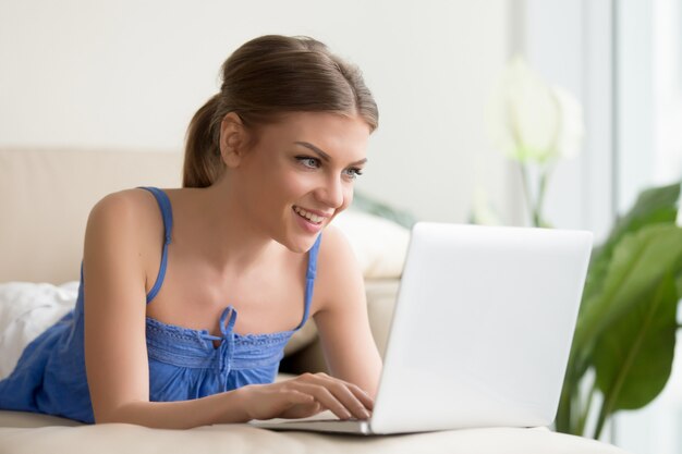 Femme jouant à des jeux sur ordinateur portable à la maison