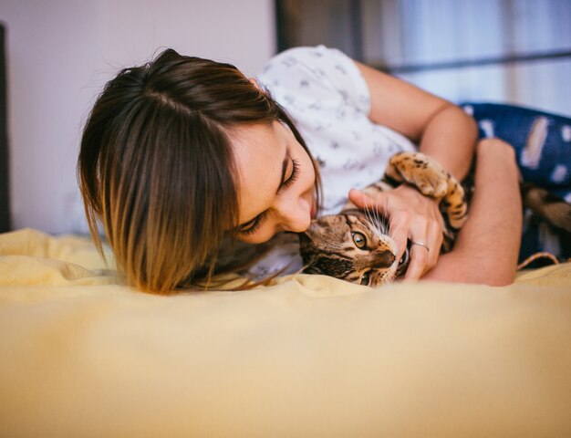 Femme joue avec le chat Bengal sur le lit