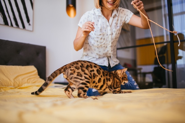 Femme joue avec une corde avec un chat Bengal