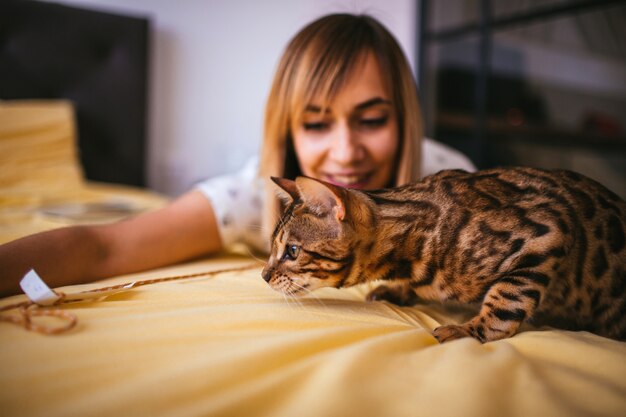 Femme joue avec une corde avec un chat Bengal