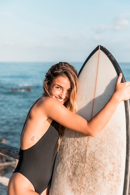 Femme Joyeuse étreignant Avec Planche De Surf Près De La Mer
