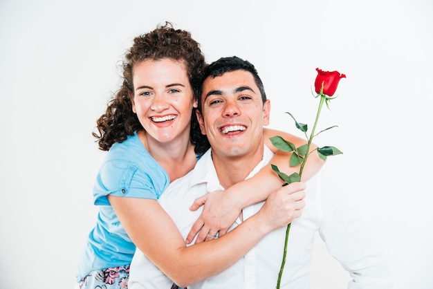 Femme joyeuse avec fleur étreignant homme souriant