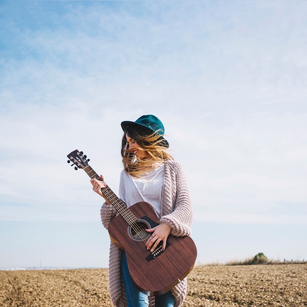 Femme joyeuse avec guitare dans la campagne