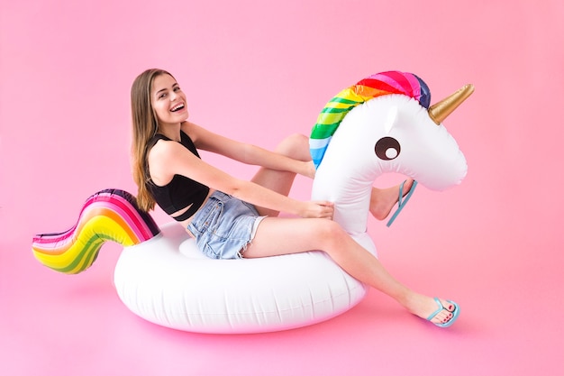 Femme joyeuse sur une licorne gonflable