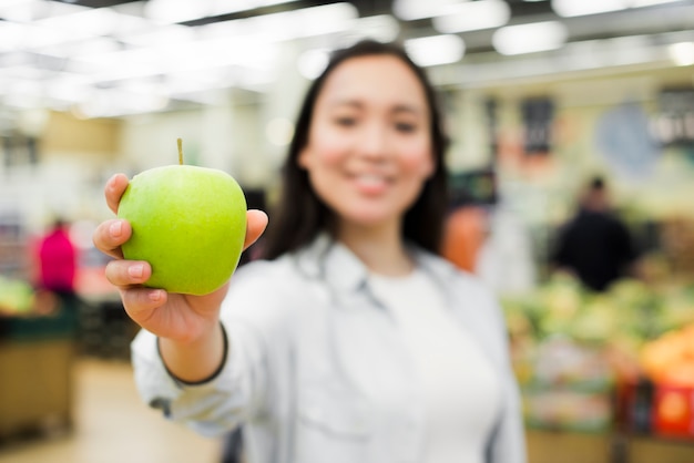 Photo gratuite femme joyeuse montrant la pomme à la caméra