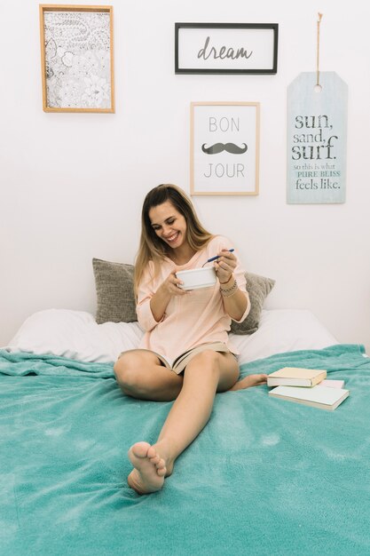 Femme joyeuse prenant son petit déjeuner et livre de lecture