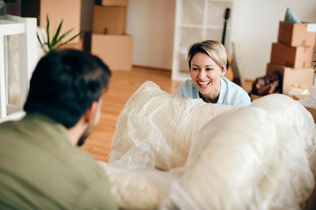 Femme joyeuse s'amusant avec son mari en emménageant dans un nouvel appartement