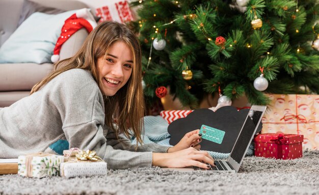 Femme joyeuse shopping en ligne et regardant la caméra